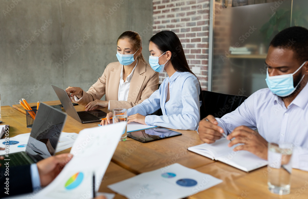 Business People In Protective Face Masks Having Corporate Meeting In Office Business People In Protective Face Masks Having Corporate Meeting In Office