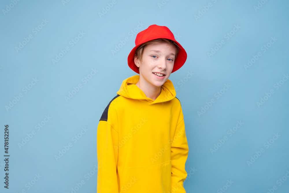 Portrait surprised young guy in yellow sweater and red panama hat on a blue background, looking at the camera with a smile on his face. Caucasian teenager posing in studio close-up studio portrait Portrait surprised young guy in yellow sweater and red panama hat on a blue background, looking at the camera with a smile on his face. Caucasian teenager posing in studio close-up studio portrait