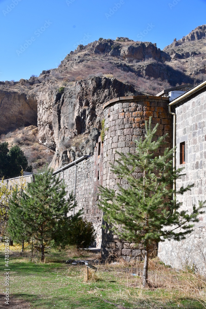 Panoramic view of the old monastery in the mountains. A high wall of stone blocks and a corner tower.