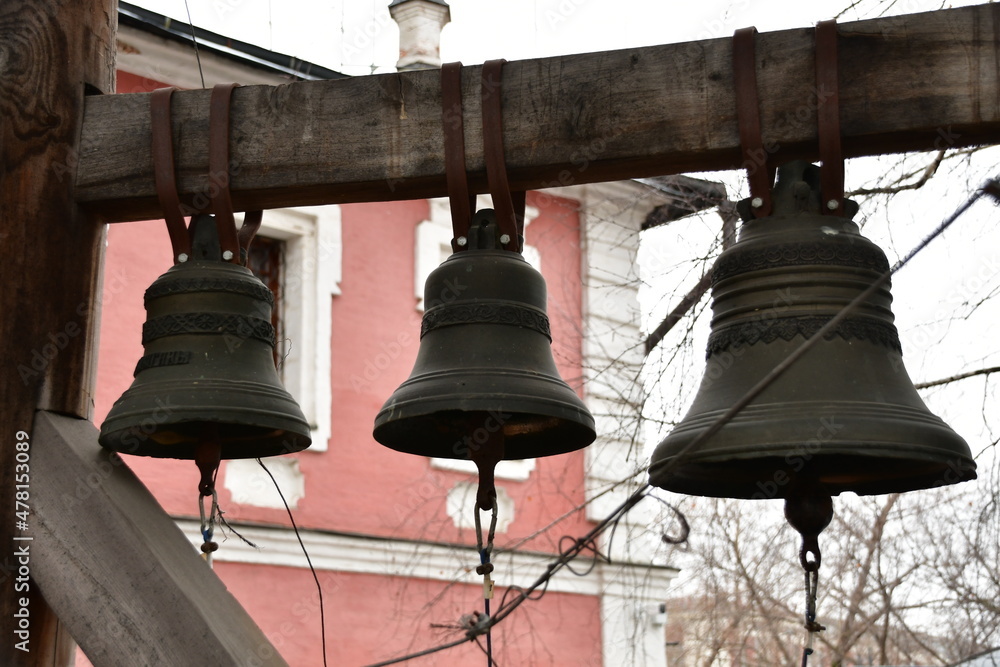 Close-up of the bells. The bells are suspended from a wooden beam. Bells with metallic patterns.