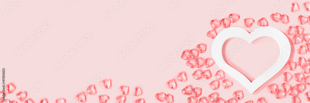St Valentines day pink background banner. Many glass hearts within white heart frame flat lay. Love or wedding concept