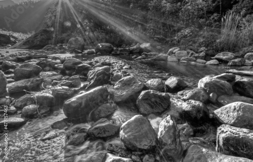 River water flowing through rocks at dawn, sun light beams on the water, beautiful Reshi River, Sikkim, India - black and white stock image of rivers in India photo