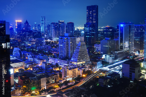 Nighttime in Bangkok city at night in Thailand. Aerial view of cityscape. Modern buildings, urban architecture and road traffic.