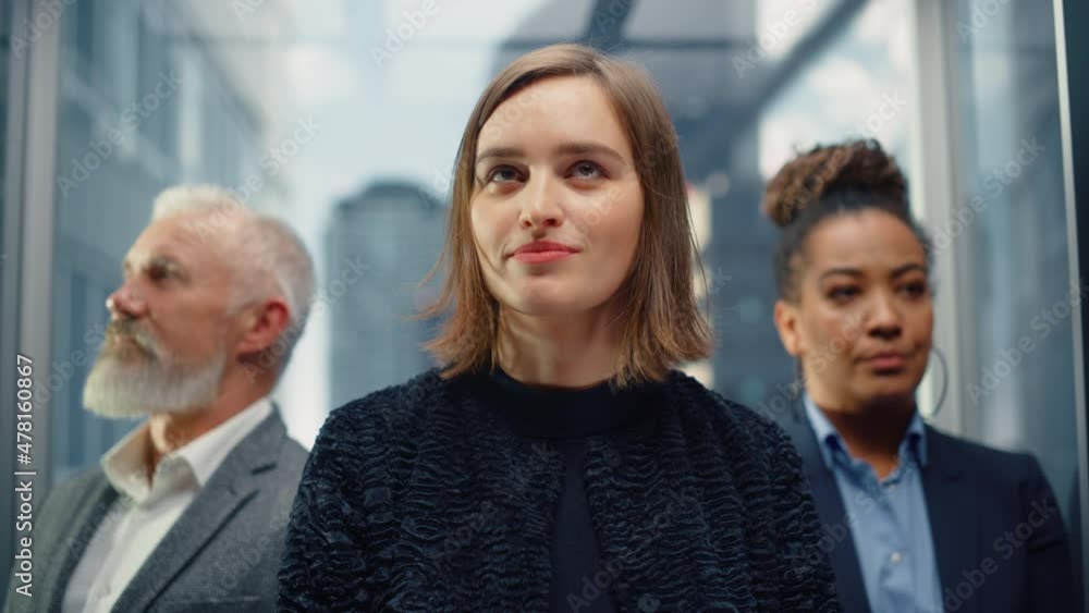 Three Diverse Multiethnic International People Ride a Glass Elevator to Office in a Modern Business Center. Focus on Different Businesspeople Standing in a Lift. Three Diverse Multiethnic International People Ride a Glass Elevator to Office in a Modern Business Center. Focus on Different Businesspeople Standing in a Lift.