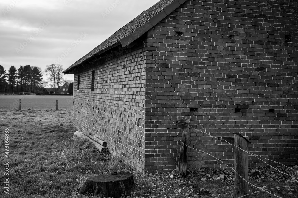 Old wind warped brick barn in black and white 