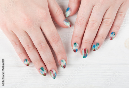 Female hands with stylish manicure closeup. Colorful nail art on wooden background.	