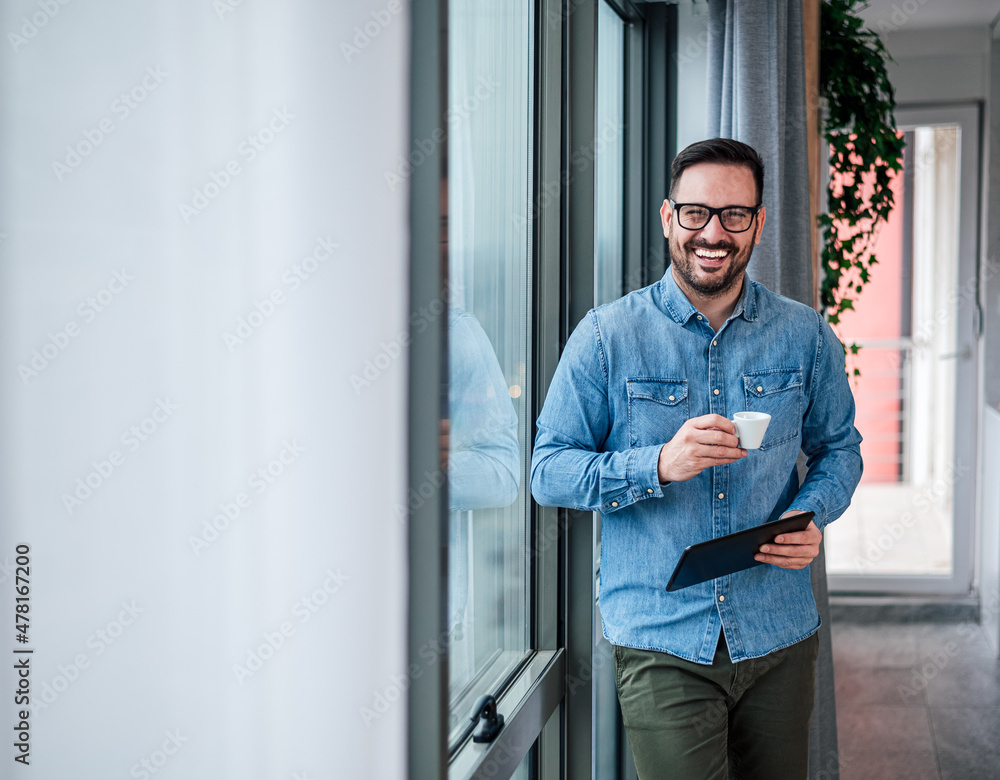 Portrait of young adult smiling cheerful businessman in home office drinking coffee morning routine starting day happy handsome successful entrepreneur freelancer checking his business tasks for day Portrait of young adult smiling cheerful businessman in home office drinking coffee morning routine starting day happy handsome successful entrepreneur freelancer checking his business tasks for day