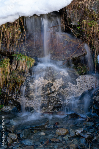 arctic landscape of frozen water from a mountain creek in long exposure photography at a cold winter day