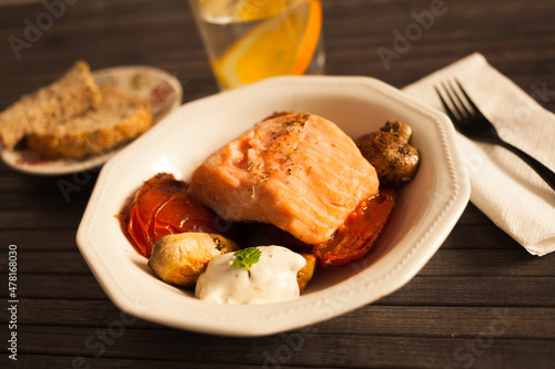 simmered slice of salmon with tomato spinon and coconut sauce in a white bowl