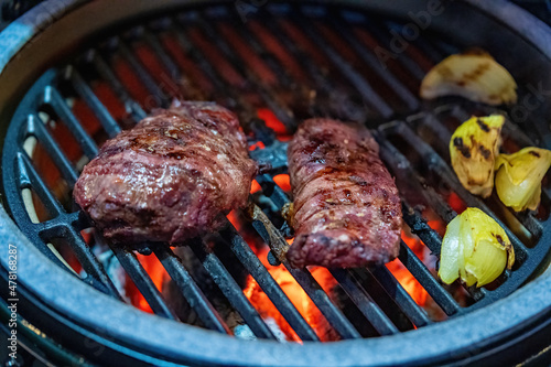 smoking venison meat and onions on a ceramic grill with charcoal