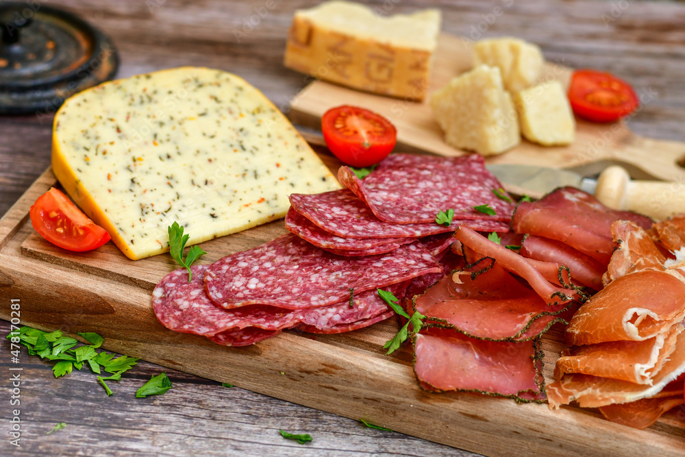 Italian  dried thinly sliced   artisan  pork Salami Milano ,  mediterranean Parmesan cheese, tomatoes   and fresh basil on wooden background .Rustic  home made Italian snack.