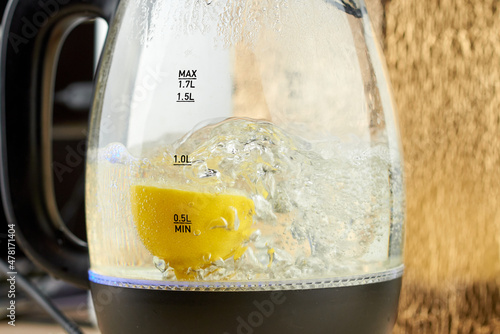 Half a yellow lemon is boiled in a glass electric kettle for descaling