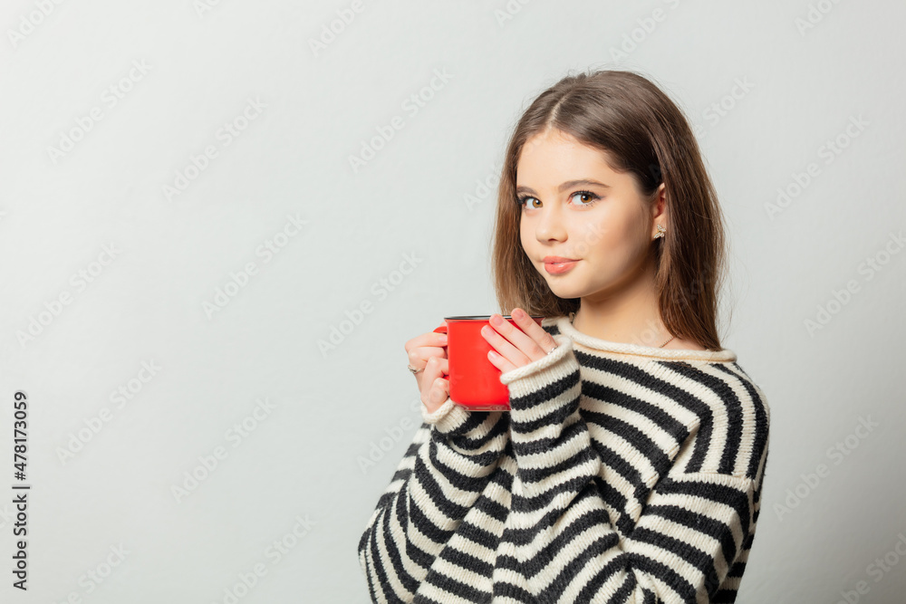 Beautiful girl in striped sweater with red mug on white background Beautiful girl in striped sweater with red mug on white background