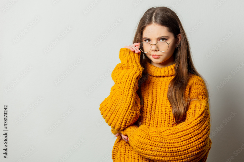 Beautiful girl in glasses and yellow sweater on white background Beautiful girl in glasses and yellow sweater on white background
