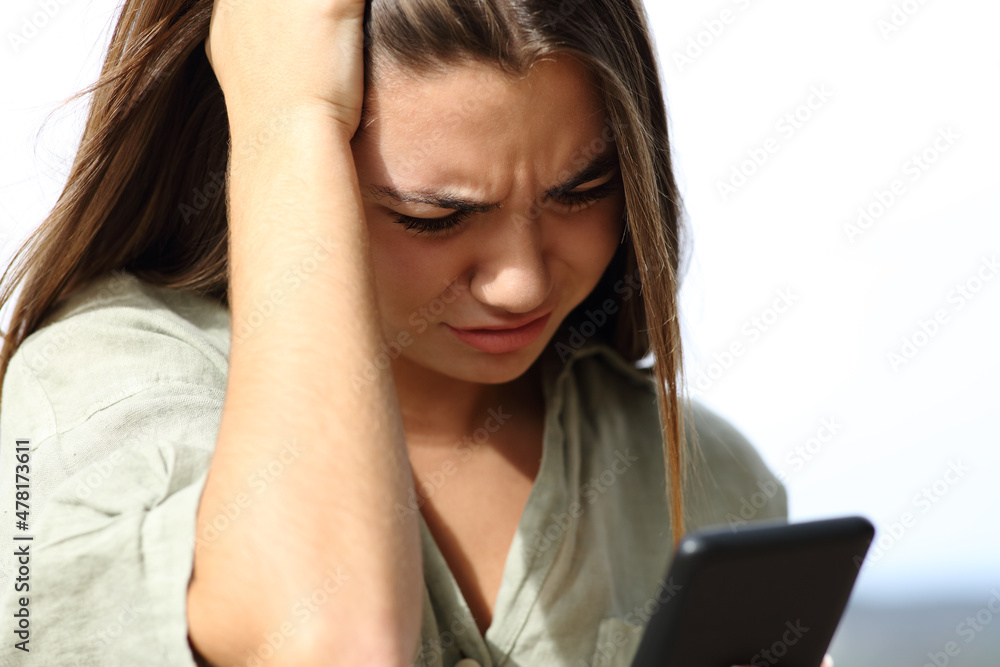 Worried teen checking news on phone outdoors