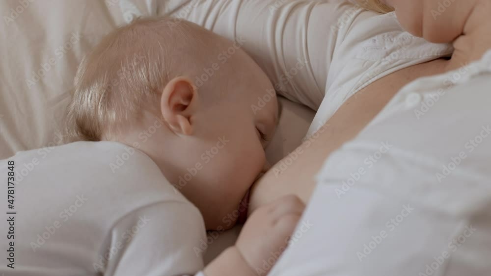 Close-up adorable toddler sleeping and drinking milk from mother breast. Concept of breastfeeding, maternity and child healthcare. Young woman feeding her baby boy Close-up adorable toddler sleeping and drinking milk from mother breast. Concept of breastfeeding, maternity and child healthcare. Young woman feeding her baby boy