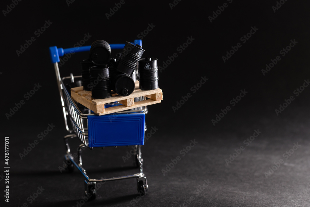 Small shopping cart and barrels isolated on dark background Small shopping cart and barrels isolated on dark background