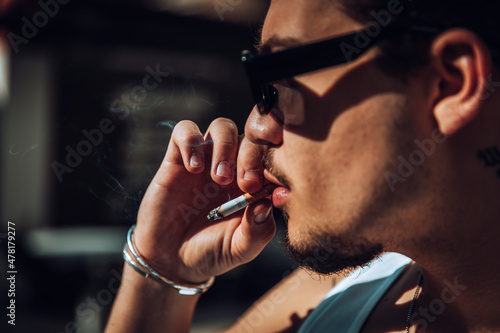 Close-up of a tattooed guy with sunglasses smoking photo