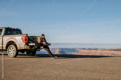 Woman leans against tailgate of pickup truck looking at view, Utah photo