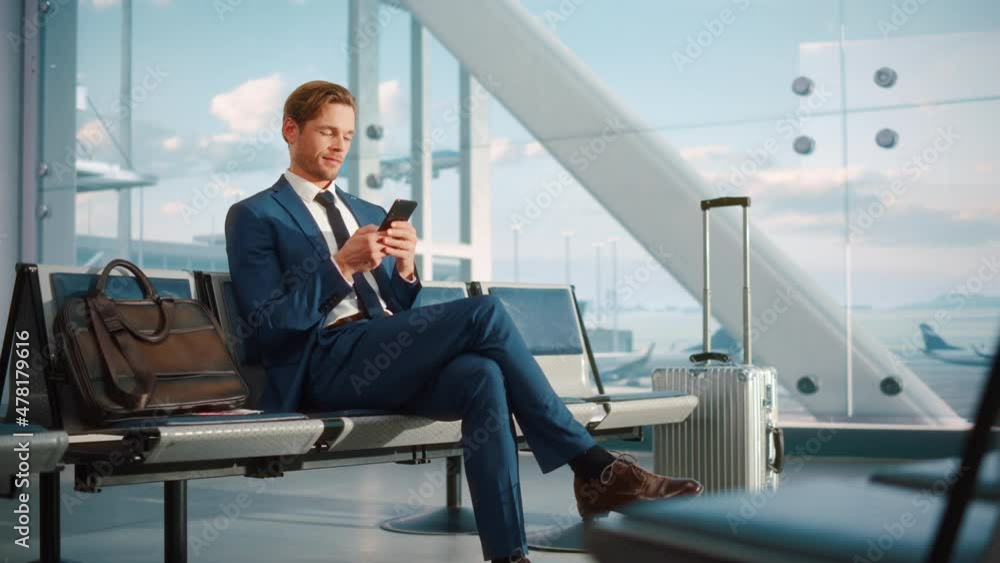 Airport Terminal Flight Wait: Smiling Businessman Uses Smartphone for e-Business, Browsing Internet with an App. Traveling Entrepreneur Work Online on Mobile Phone in Boarding Lounge of Airline Hub Airport Terminal Flight Wait: Smiling Businessman Uses Smartphone for e-Business, Browsing Internet with an App. Traveling Entrepreneur Work Online on Mobile Phone in Boarding Lounge of Airline Hub