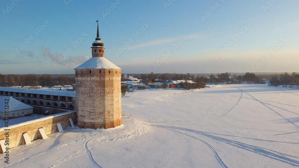 Beautiful winter landscape with a view of the tower of an ancient Orthodox monastery, frozen lake