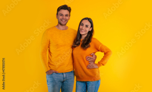 Holiday with my beloved. Lovely young couple in love is celebrating Valentine’s Day wearing yellow sweaters, hugging each other and laughing together while they isolated in studio