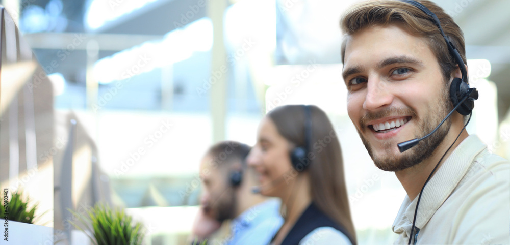 Portrait of call center worker accompanied by his team. Smiling customer support operator at work. Portrait of call center worker accompanied by his team. Smiling customer support operator at work.