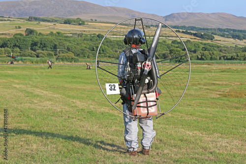 Paramotor pilot taking off from a field 