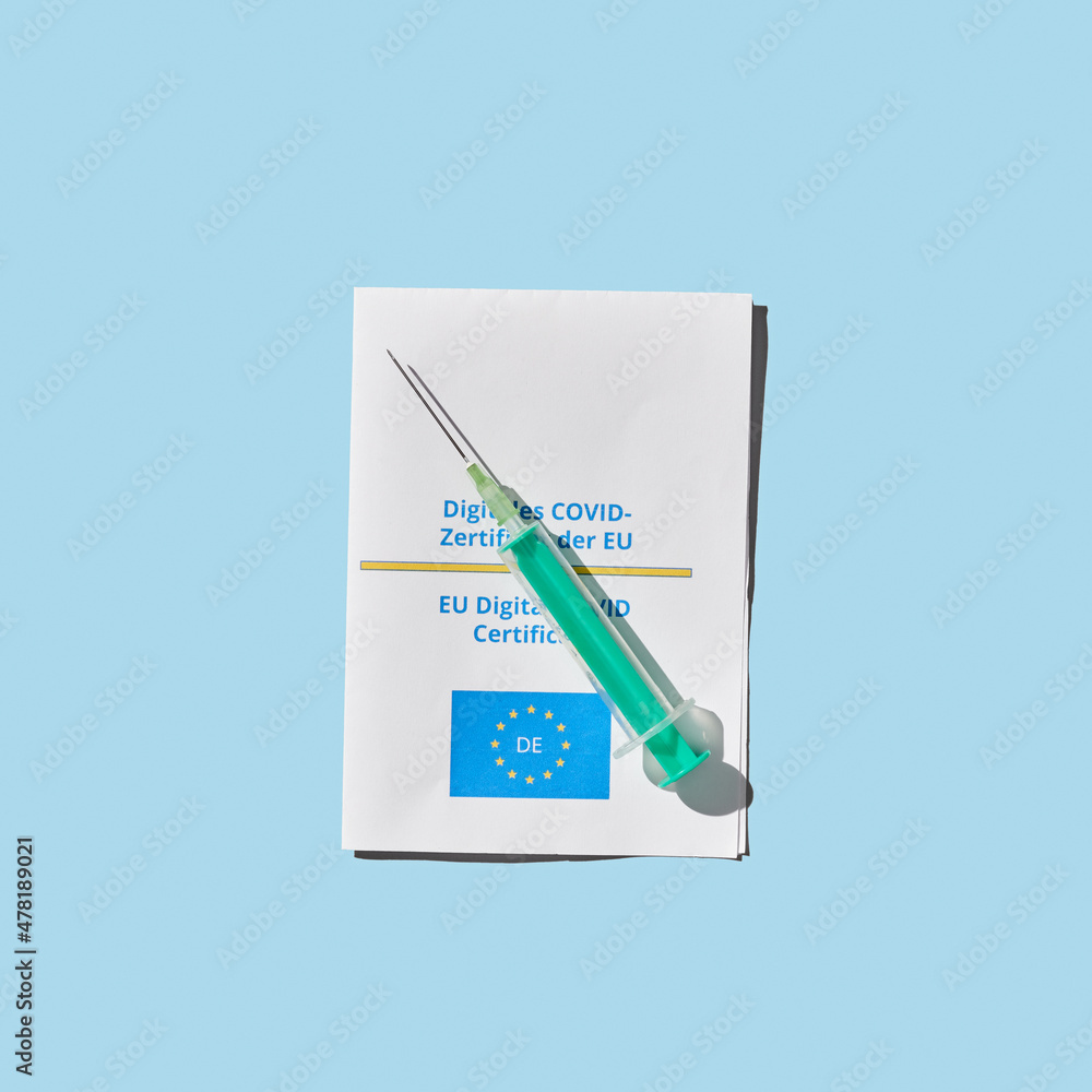 vaccine concept with syringe and EU certificate of vaccination on blue background vaccine concept with syringe and EU certificate of vaccination on blue background