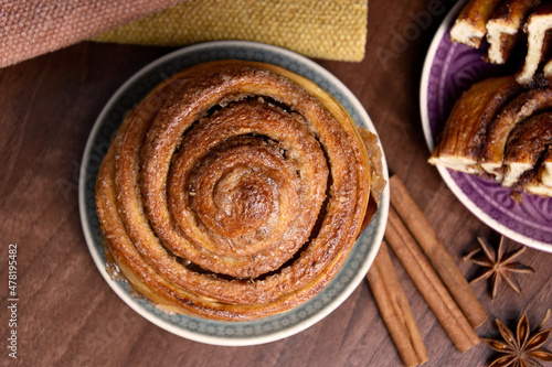 Cinnamon roll sweet pastry with spices on the table top view stock images. Delicious fresh cinnamon bun on a plate still life above stock photo