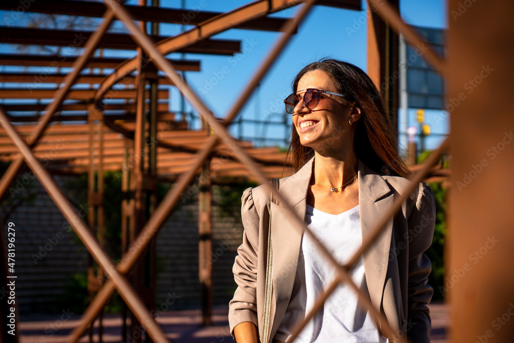 Young woman in brown suit and white t-shirt behind a rusty fence