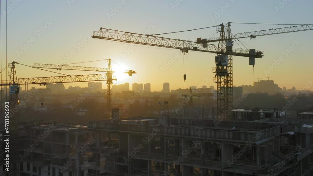 Aerial view of a large construction of a residential area with many multi-storey buildings under construction, a lot of tower cranes, workers, construction equipment at sunset Aerial view of a large construction of a residential area with many multi-storey buildings under construction, a lot of tower cranes, workers, construction equipment at sunset