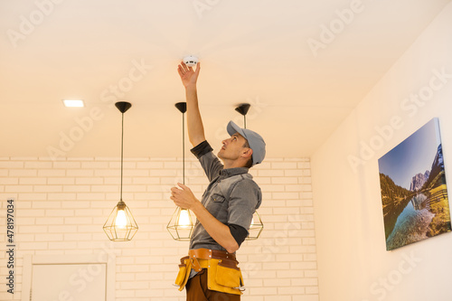 Fotografi Handyman installing a smoke detector on the ceiling