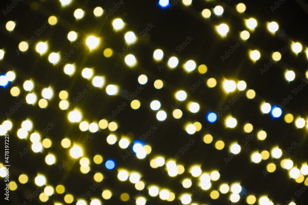 Background. Blurred Yellow Christmas lights on a black background. Yellow garland. New Year's illumination. Concept of New Year celebration. Copy space for your design