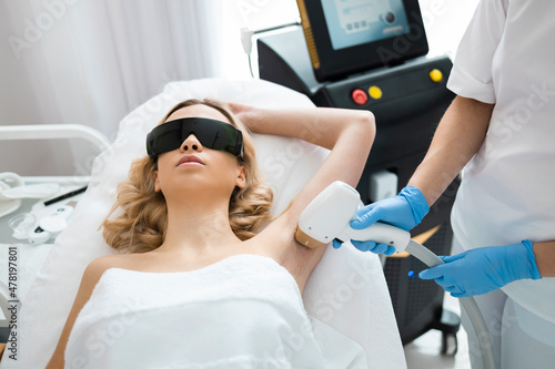 Beautiful girl on a laser hair removal procedure armpits in cosmetology salon. Smooth and silky skin concept photo