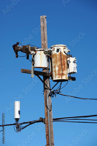 Close-up view of the top of a wooden seaside electricity pylon with some rusty weathered transformer units