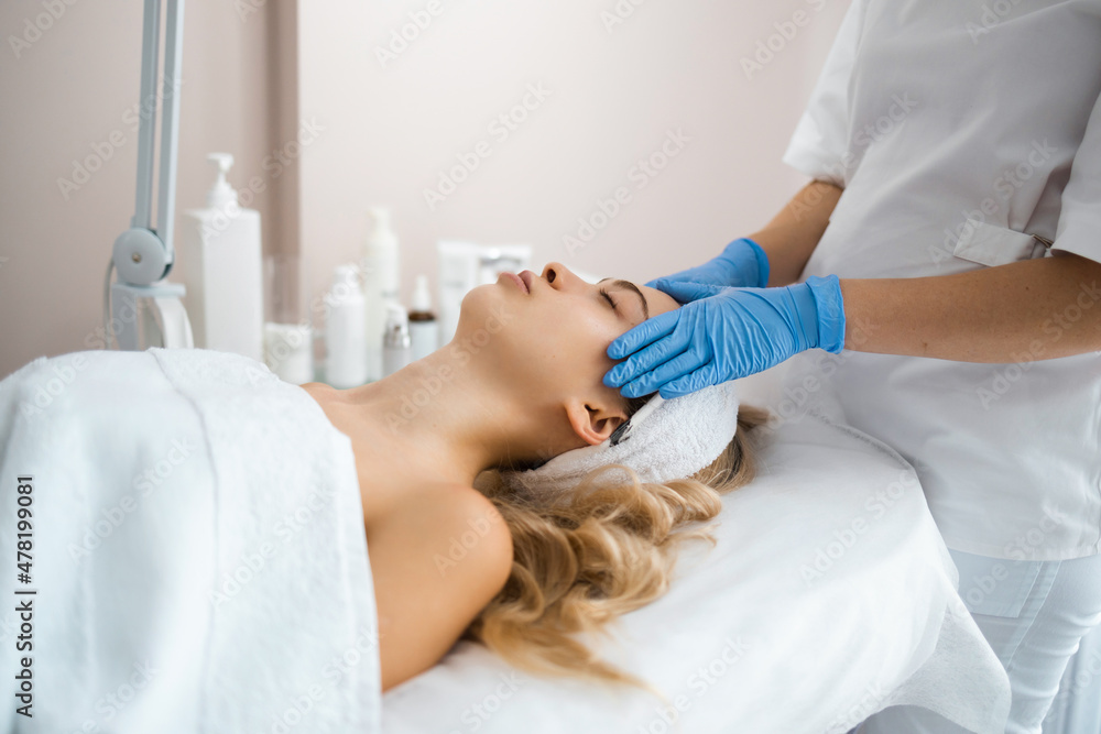 Obraz premium Beautician massaging the face of young girl in latex gloves. Masseur doing relax facial massage at spa salon