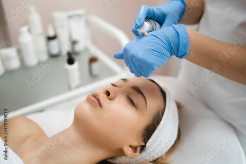 Cosmetologist squeezing out a tube of cream. Skin care concept. Relaxed woman lies on the couch of the spa salon