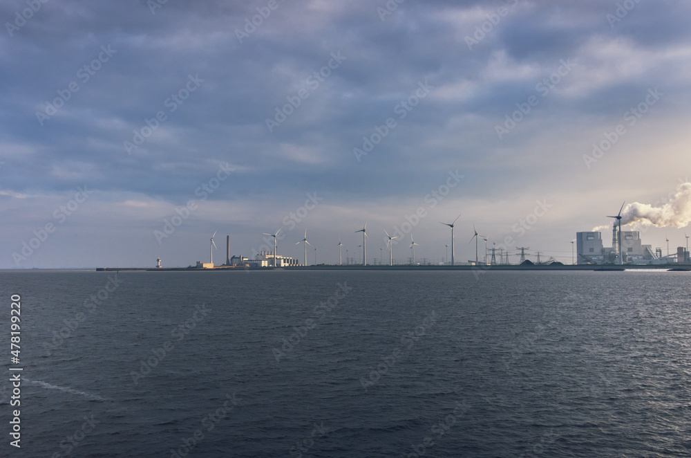 Wind turbine - the sky and the sea, the sun breaks through the clouds, cargo ship at sea