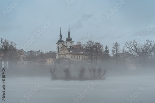 Foggy morning at Premonstratensian Zeliv Monastery,national heritage site,popular place of pilgrimage.Calm site for spiritual regeneration and physical relaxation.Misty landscape by water,cold weather photo