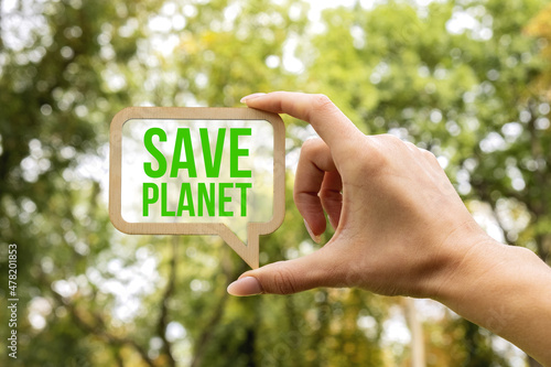 A woman's hand holds a sign inside which the inscription - Save Planet. Closeup of wooden speech buble with words Save planet. Green planet in your hands. Environment concept.