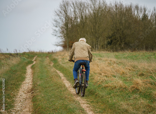 a casual push bike cyclist riding along an unmade track crossing open countryside, salisbury plain, Wiltshire UK