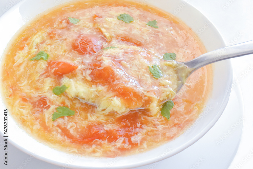 Tomato egg drop soup in a white bowl. Traditional Chinese food. Tomato egg drop soup in a white bowl. Traditional Chinese food.