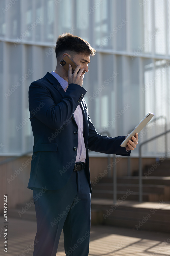 Serious young business man on a phone call with a concentrated face on a tablet Serious young business man on a phone call with a concentrated face on a tablet