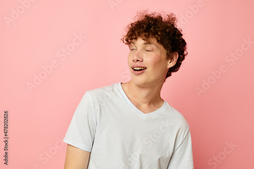 portrait of a young curly man in white t-shirt casual wear emotions pink background unaltered