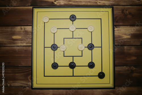 Top down view on gameboard with black and white pieces of strategy game for two people - nine men's morris or mills