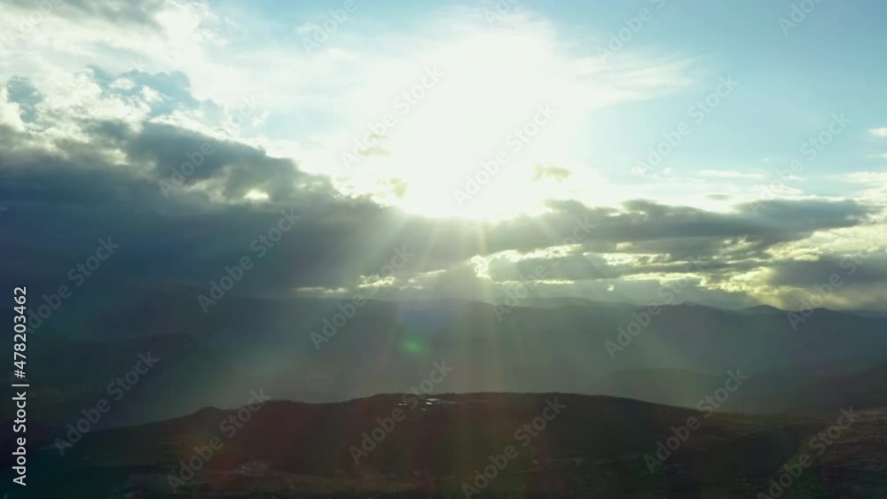 Aerial view Beautiful sunlight in the mountains. Landscape with mountain ranges and peaks and clouds through which the sun's rays break through. Aerial view Beautiful sunlight in the mountains. Landscape with mountain ranges and peaks and clouds through which the sun's rays break through.