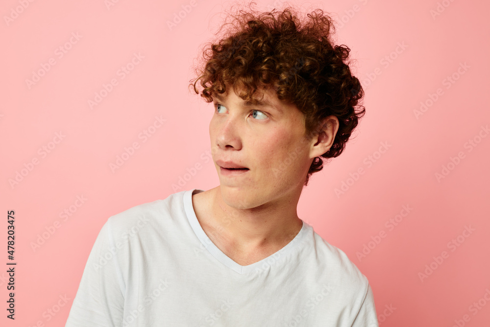 portrait of a young curly man in white t-shirt casual wear emotions pink background unaltered portrait of a young curly man in white t-shirt casual wear emotions pink background unaltered