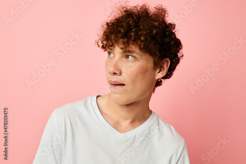 portrait of a young curly man in white t-shirt casual wear emotions pink background unaltered