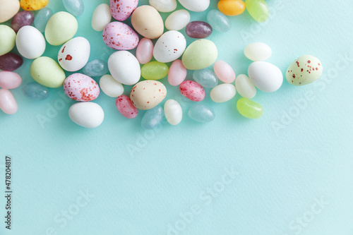 Happy Easter concept. Preparation for holiday. Easter candy chocolate eggs and jellybean sweets isolated on trendy pastel blue background. Simple minimalism flat lay top view copy space.